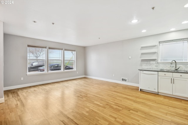 unfurnished living room featuring sink and light hardwood / wood-style floors