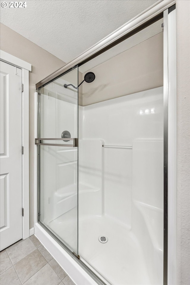 bathroom with tile patterned flooring, walk in shower, and a textured ceiling