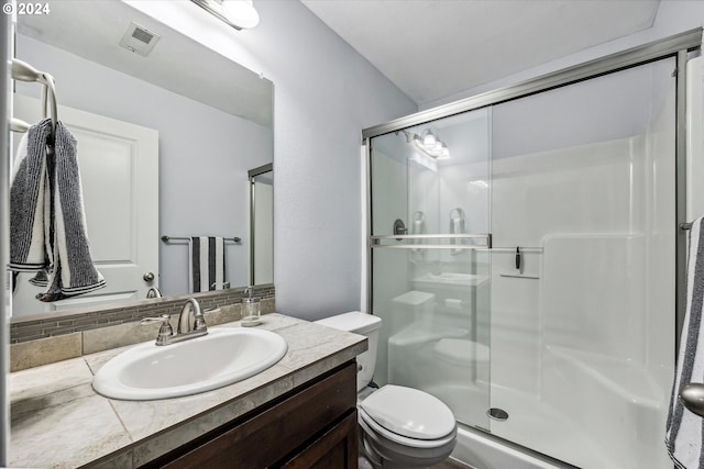 bathroom with a shower with door, vanity, and toilet