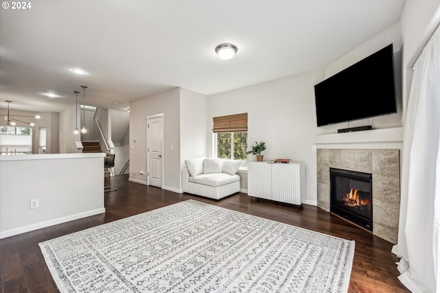 living room with a tile fireplace, an inviting chandelier, dark wood-type flooring, and radiator