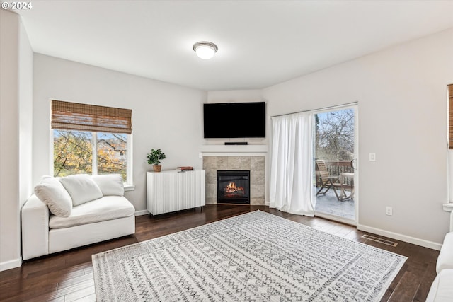 living room featuring a fireplace, radiator heating unit, and dark wood-type flooring