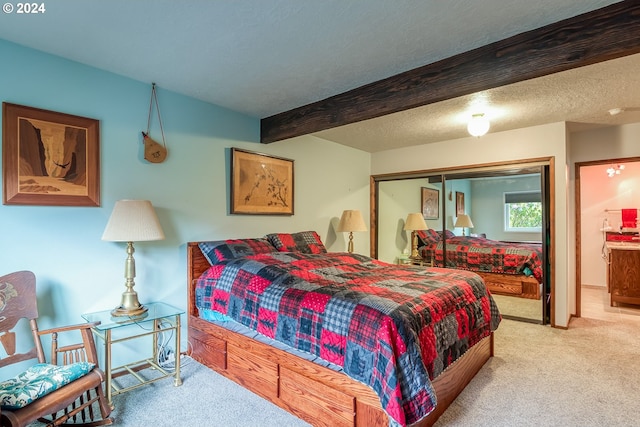 carpeted bedroom with a closet, beam ceiling, and a textured ceiling