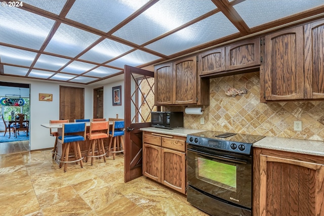 kitchen with backsplash, black appliances, coffered ceiling, and light hardwood / wood-style flooring