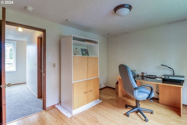 office with light hardwood / wood-style flooring and a textured ceiling