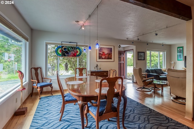 dining room with track lighting, light hardwood / wood-style floors, and a textured ceiling