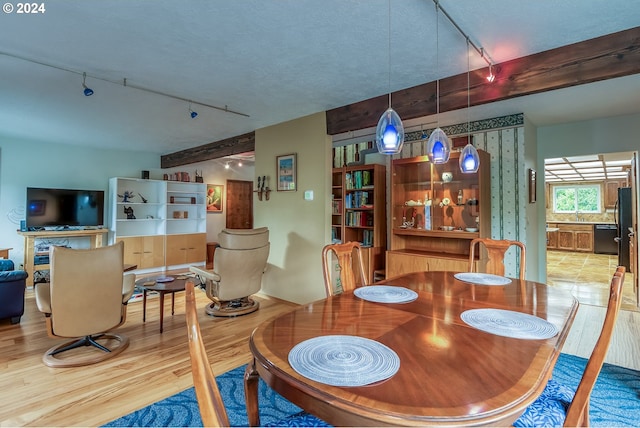 dining space with sink, a textured ceiling, track lighting, and light tile floors