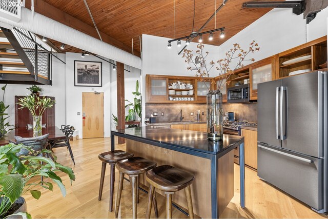 kitchen with a kitchen breakfast bar, light wood-type flooring, a high ceiling, and appliances with stainless steel finishes