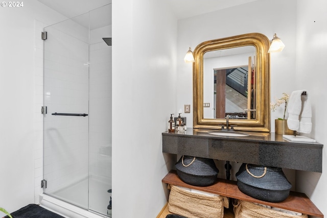 bathroom featuring a shower with shower door and sink