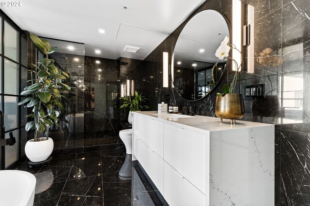 bathroom featuring backsplash, toilet, a shower with door, vanity, and tile walls