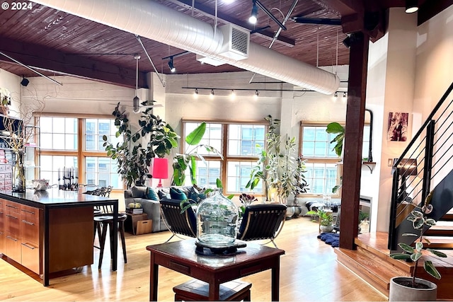 living room featuring beamed ceiling, a towering ceiling, and light hardwood / wood-style flooring