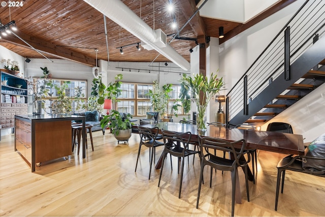 dining area featuring light hardwood / wood-style floors, wood ceiling, and a high ceiling