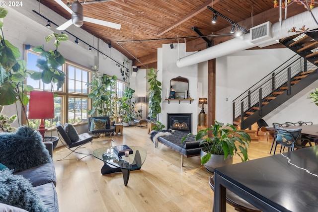 living room featuring ceiling fan, light hardwood / wood-style flooring, wood ceiling, and a high ceiling