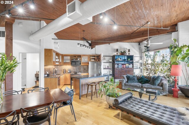 dining room with ceiling fan, sink, wooden ceiling, a towering ceiling, and light hardwood / wood-style floors