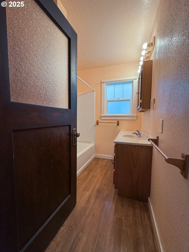 bathroom with wood-type flooring, vanity, and a textured ceiling