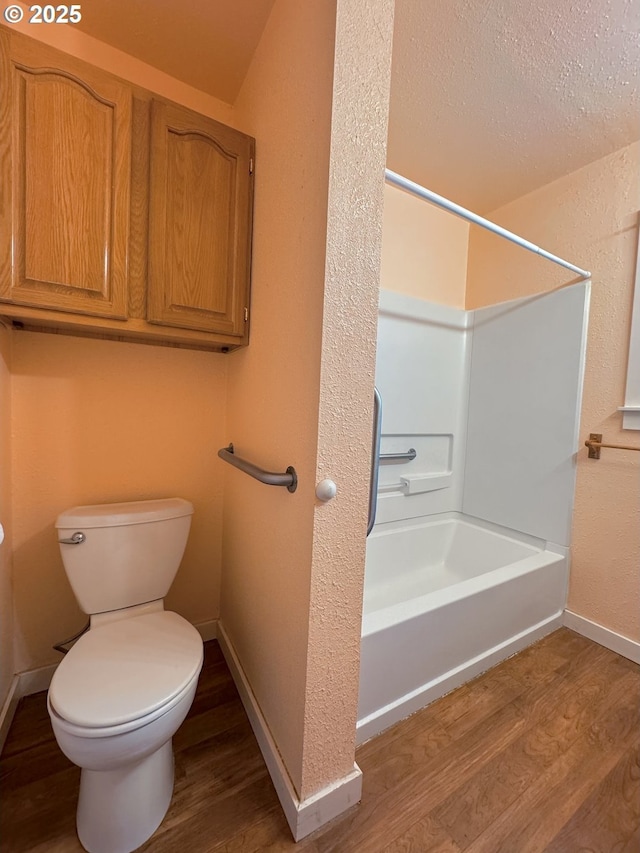 bathroom featuring shower / washtub combination, toilet, hardwood / wood-style floors, and a textured ceiling