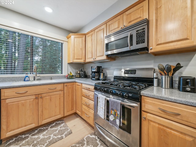 kitchen featuring appliances with stainless steel finishes, sink, light brown cabinetry, and light hardwood / wood-style floors