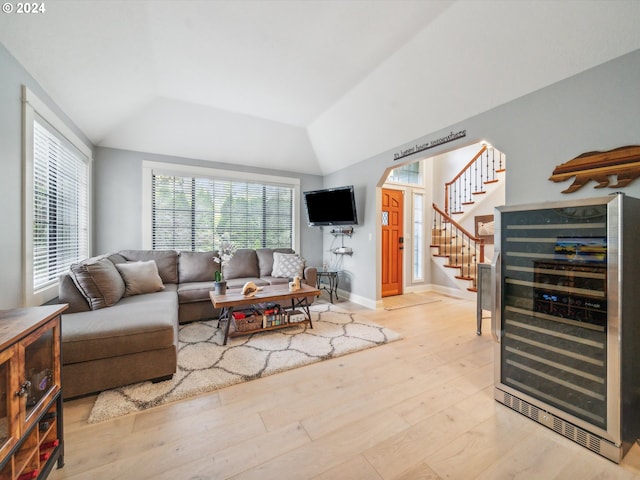 living room featuring wine cooler, lofted ceiling, and light hardwood / wood-style floors