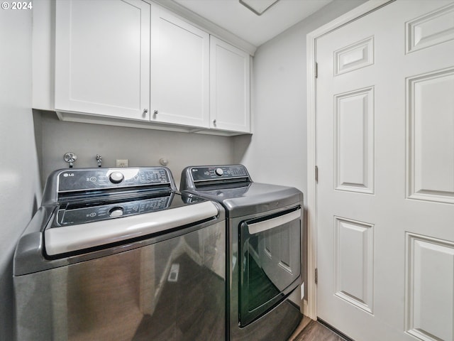 laundry area with washing machine and dryer, cabinets, and dark hardwood / wood-style floors