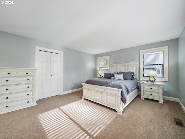 bedroom featuring a closet, multiple windows, and light colored carpet