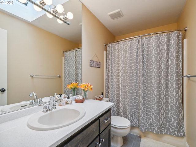 bathroom with vanity, toilet, a skylight, and a shower with shower curtain