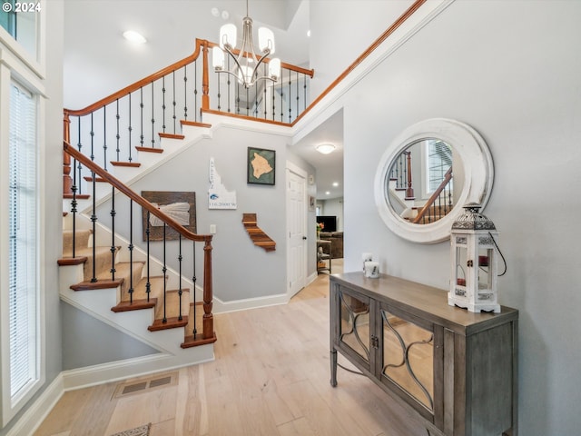 entryway featuring a notable chandelier, a high ceiling, and light wood-type flooring