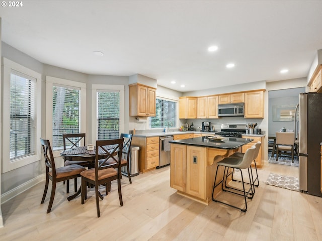 kitchen with light brown cabinetry, appliances with stainless steel finishes, a center island, and light wood-type flooring