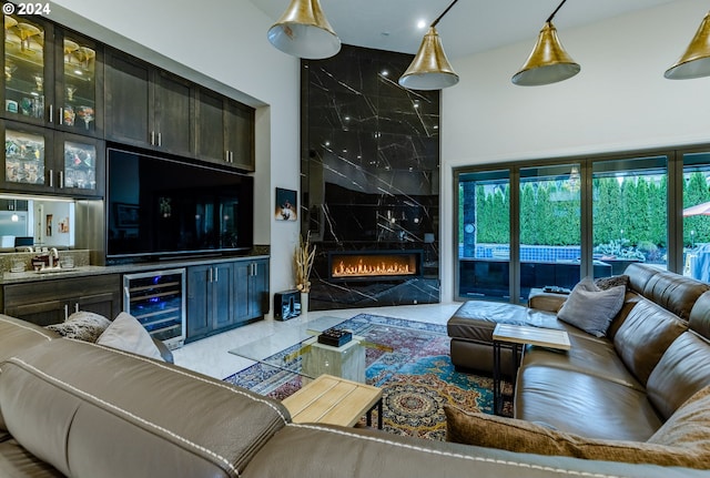 living room with wine cooler, a premium fireplace, light tile patterned flooring, and indoor wet bar