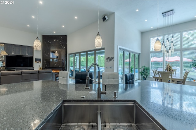 kitchen with dark stone countertops, a towering ceiling, and decorative light fixtures