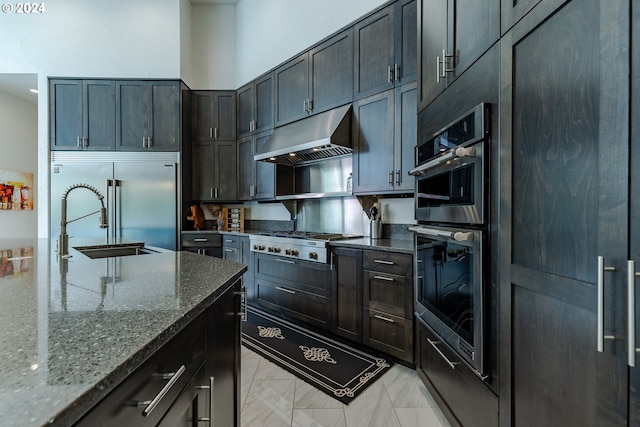 kitchen with dark stone countertops, sink, and stainless steel appliances