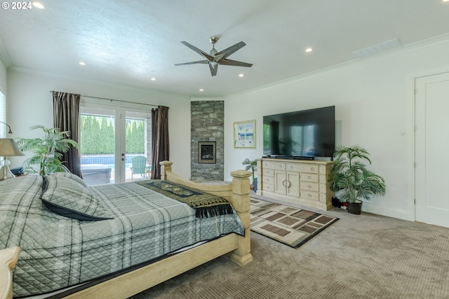 bedroom with carpet, ornamental molding, access to outside, ceiling fan, and a stone fireplace