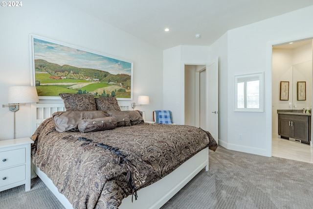 bedroom with light colored carpet and ensuite bath