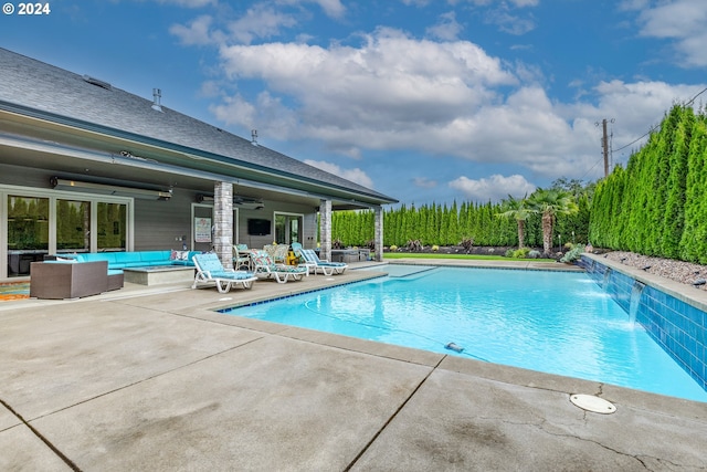 view of pool with outdoor lounge area, a patio, pool water feature, and ceiling fan