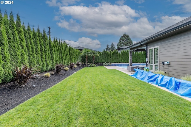 view of yard featuring a covered pool and central AC unit