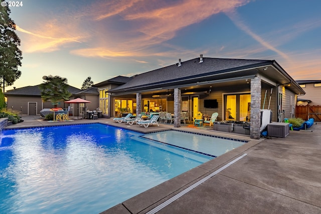 pool at dusk featuring ceiling fan and a patio