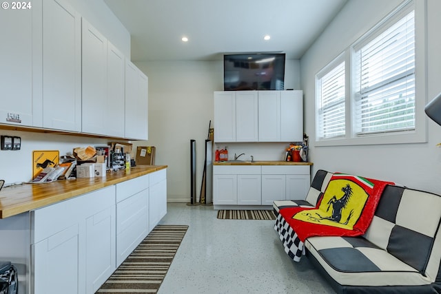 kitchen featuring white cabinets, butcher block counters, and sink