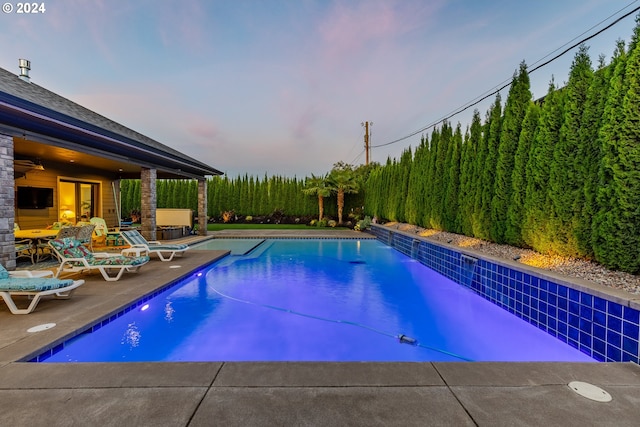 pool at dusk with a patio area