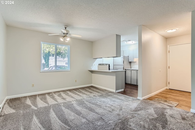 unfurnished living room with wood-type flooring, ceiling fan, and a textured ceiling