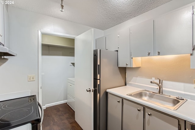 kitchen featuring sink, a textured ceiling, dark wood-type flooring, range, and washer / dryer