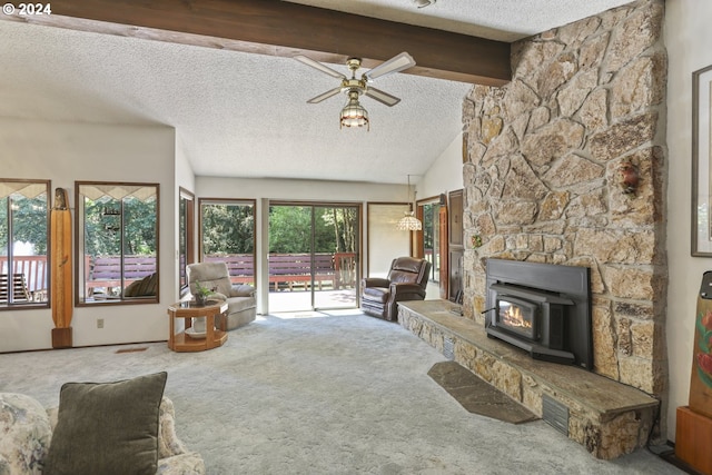 carpeted living room with lofted ceiling with beams, a fireplace, a wood stove, a textured ceiling, and ceiling fan