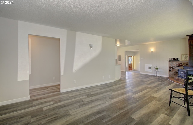 living room featuring wood-type flooring, a textured ceiling, and a wood stove