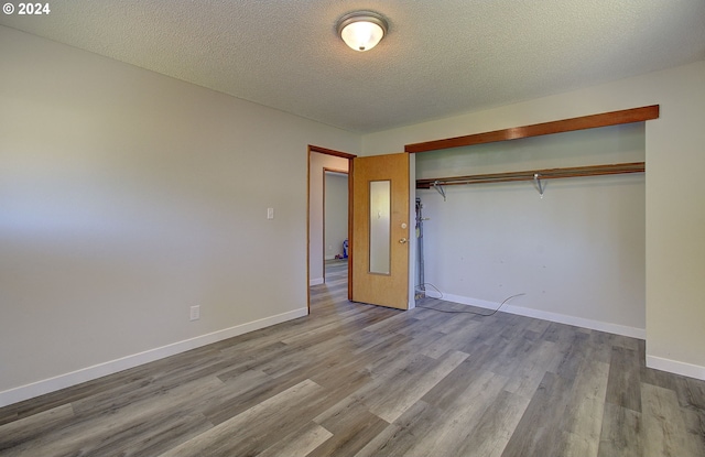 unfurnished bedroom featuring a closet, a textured ceiling, and light hardwood / wood-style flooring