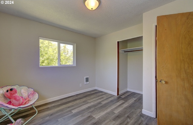 unfurnished bedroom featuring wood-type flooring, a textured ceiling, and a closet