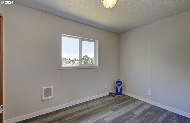 unfurnished room with wood-type flooring and a textured ceiling