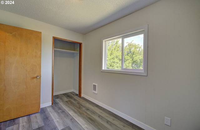 unfurnished bedroom with a textured ceiling, light hardwood / wood-style flooring, and a closet