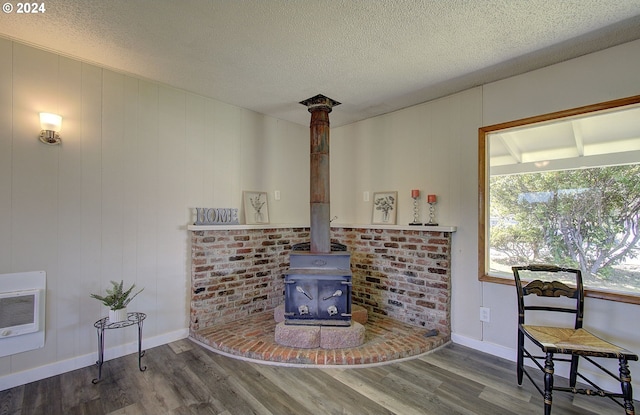 living room featuring wood-type flooring, a textured ceiling, heating unit, and a wood stove