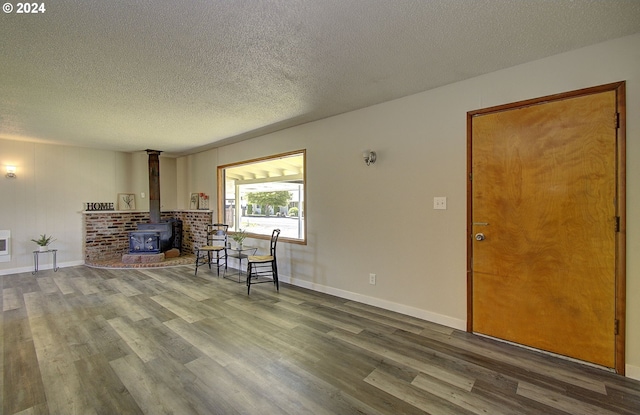 living room with hardwood / wood-style floors, a wood stove, a textured ceiling, and heating unit