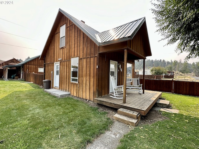 rear view of property featuring a wooden deck and a lawn