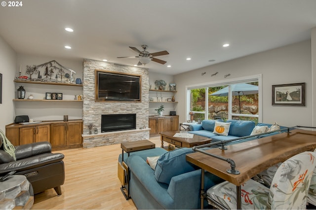 living room with a fireplace, ceiling fan, and light hardwood / wood-style flooring