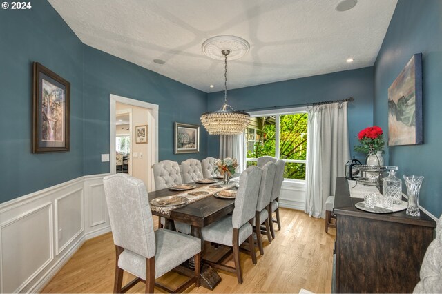 dining room with an inviting chandelier, a textured ceiling, and light wood-type flooring