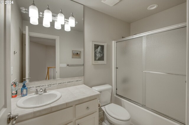 full bathroom with vanity, toilet, and bath / shower combo with glass door